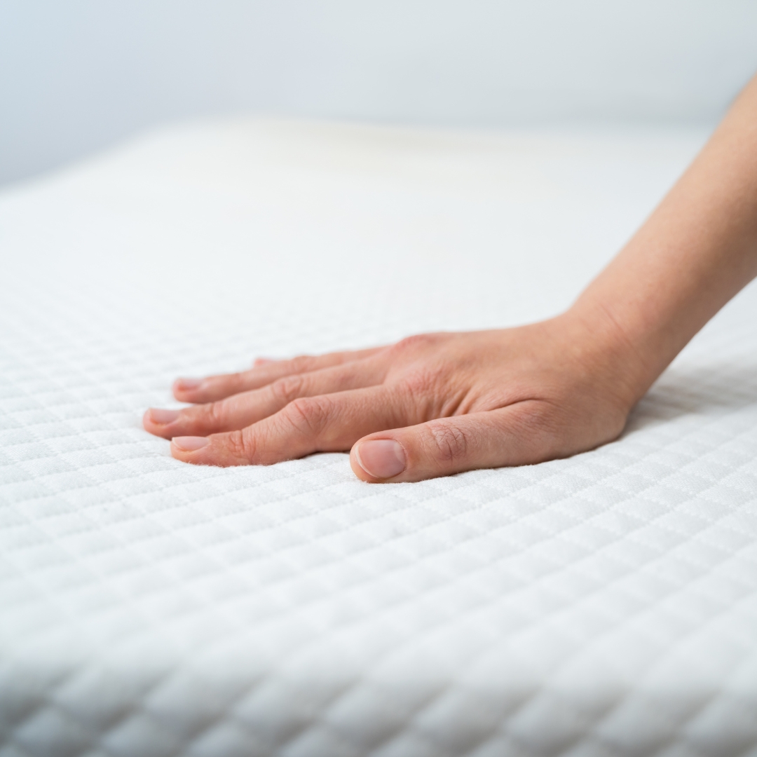 Close up of a hand resting on a mattress