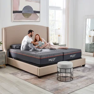 Couple lounging on a split-king MLILY bed with grey mattresses and red piping in a bright, modern bedroom.
